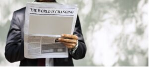 A person reading a newspaper with a headline that reads, "The World is Changing"