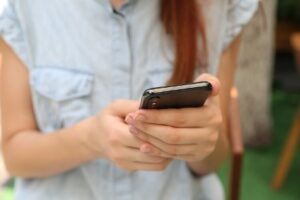 Person on cell phone and using DBT skills to keep in contact with others through Zoom, FaceTime, Skype and other social platforms instead of feeling isolated