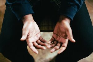 A person sitting in a chair with their hands in their lap and opened up toward the ceiling insinuating open communication and willing hands to feel calmer