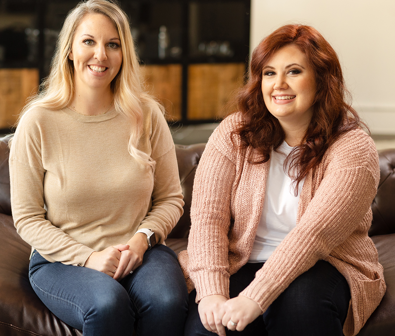 dr-nikki-winchester-and-dr-desirae-allen-dbt-therapists Dr. Nikki Winchester and Dr. Desirae Allen, DBT Therapists, sit on a couch and smile.