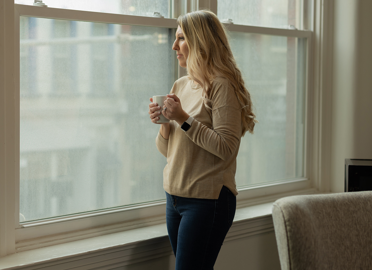 Dr. Desirae Allen, DBT therapist, holds a coffee cup and looks out the window, thinking about how DBT can be helpful for depression