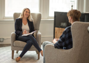 Dr. Desirae Allen, DBT therapist, sitting in an accent chair across from a DBT client, providing adherent DBT