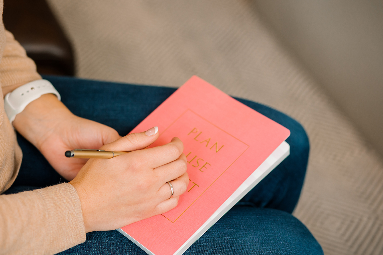 Pink notebook rests in a clinician's lap as they take notes during an individual CBT therapy session for depression