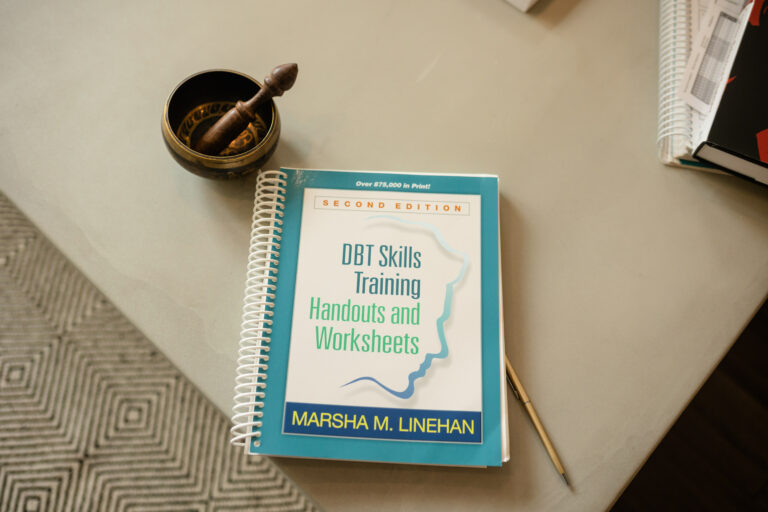 Photo of DBT Skills Training Handouts and Worksheets by Marsha Linehan and mindfulness bowl. These are part of adherent DBT offered at Cincinnati Center for DBT