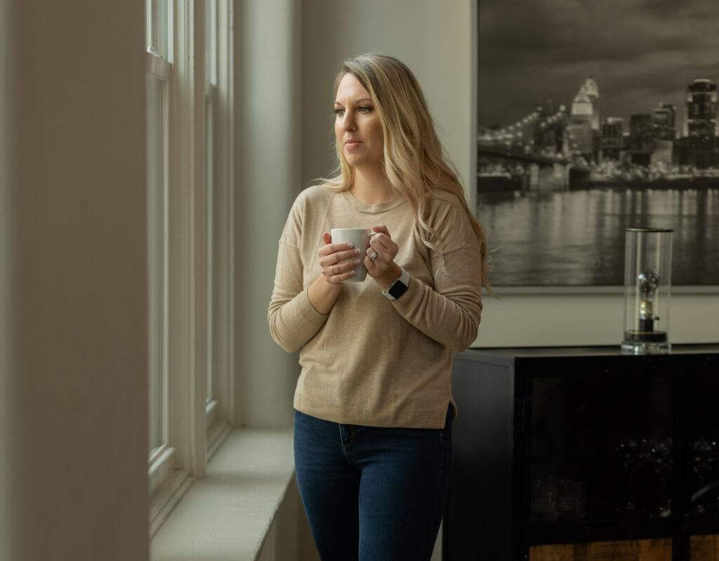 Dr. Desirae Allen, therapist for depression, looks out a window while holding a cup of coffee and thinking about the effectiveness of CBT for depression