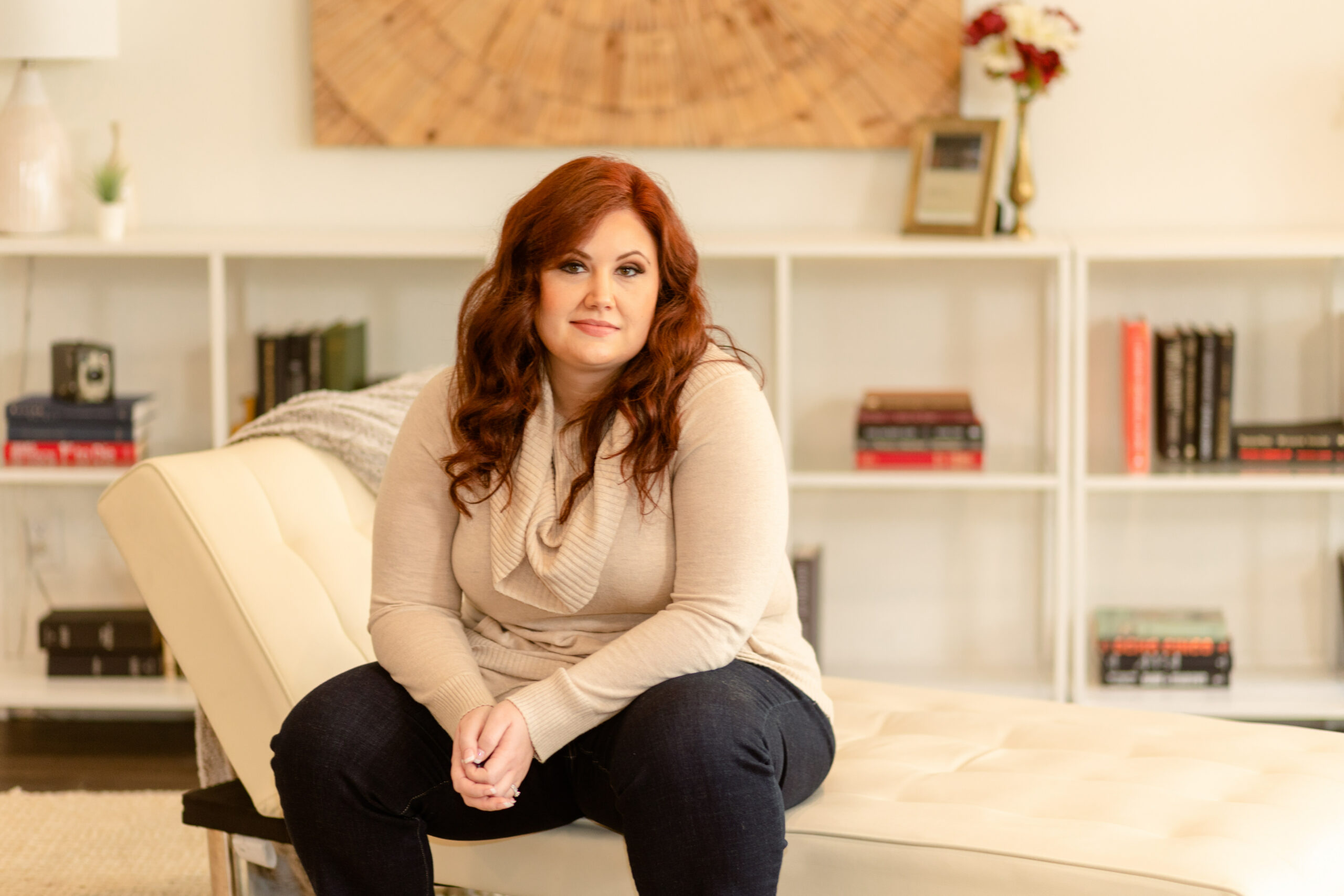 Nikki Winchester sits on a chase lounge in front of a bookshelf, ready to provide motivational interviewing (MI) and/or motivational enhancement therapy (MET) training