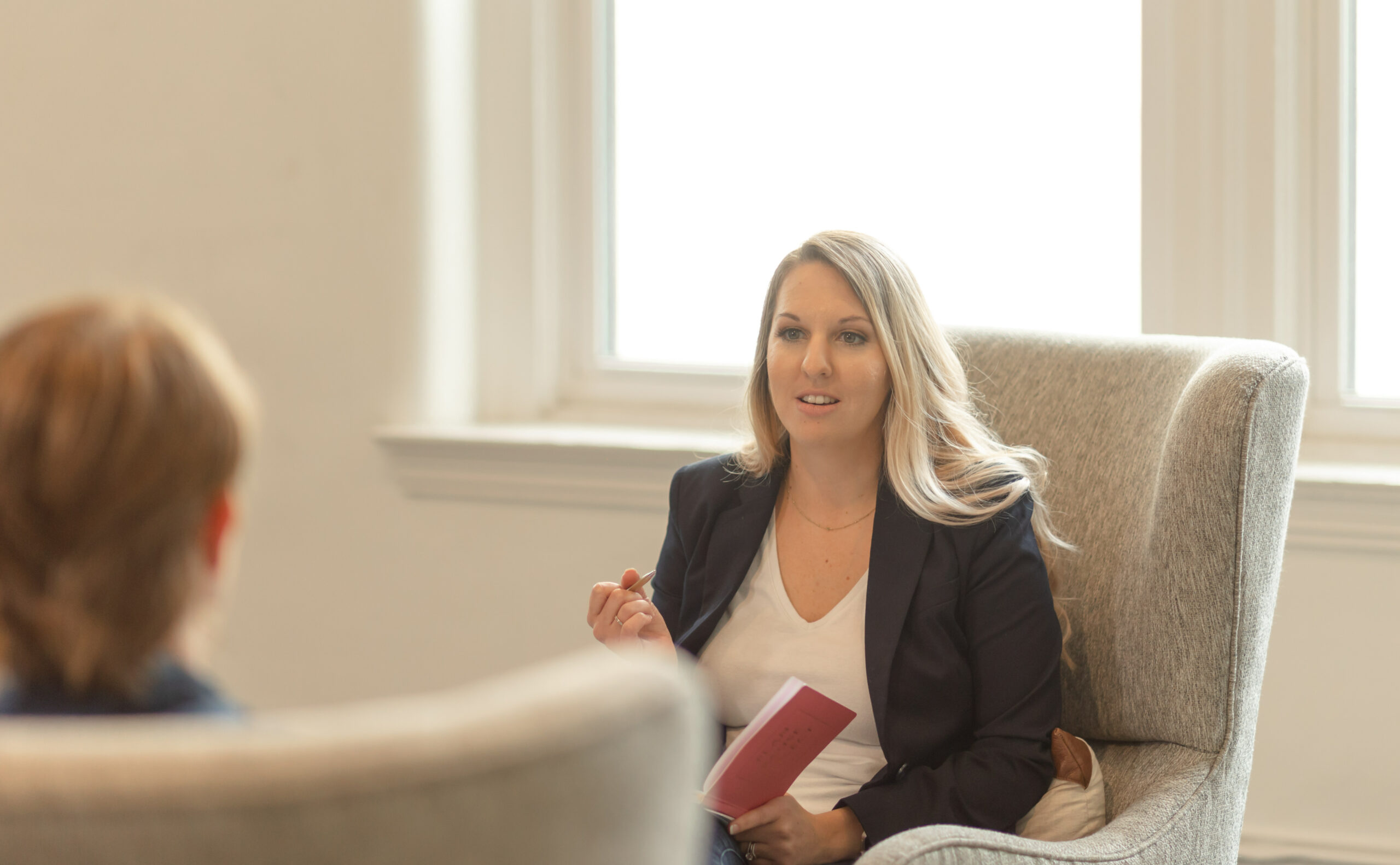 DBT-for-alcohol-use-drug-use Dr. Desirae Allen holds a notebook and pen in her hand while conducting individual therapy with a client with a substance use disorder.