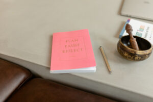 Pink journal next to pen and DBT mindfulness bell for use in planning ahead to maintain sobriety using DBT skills