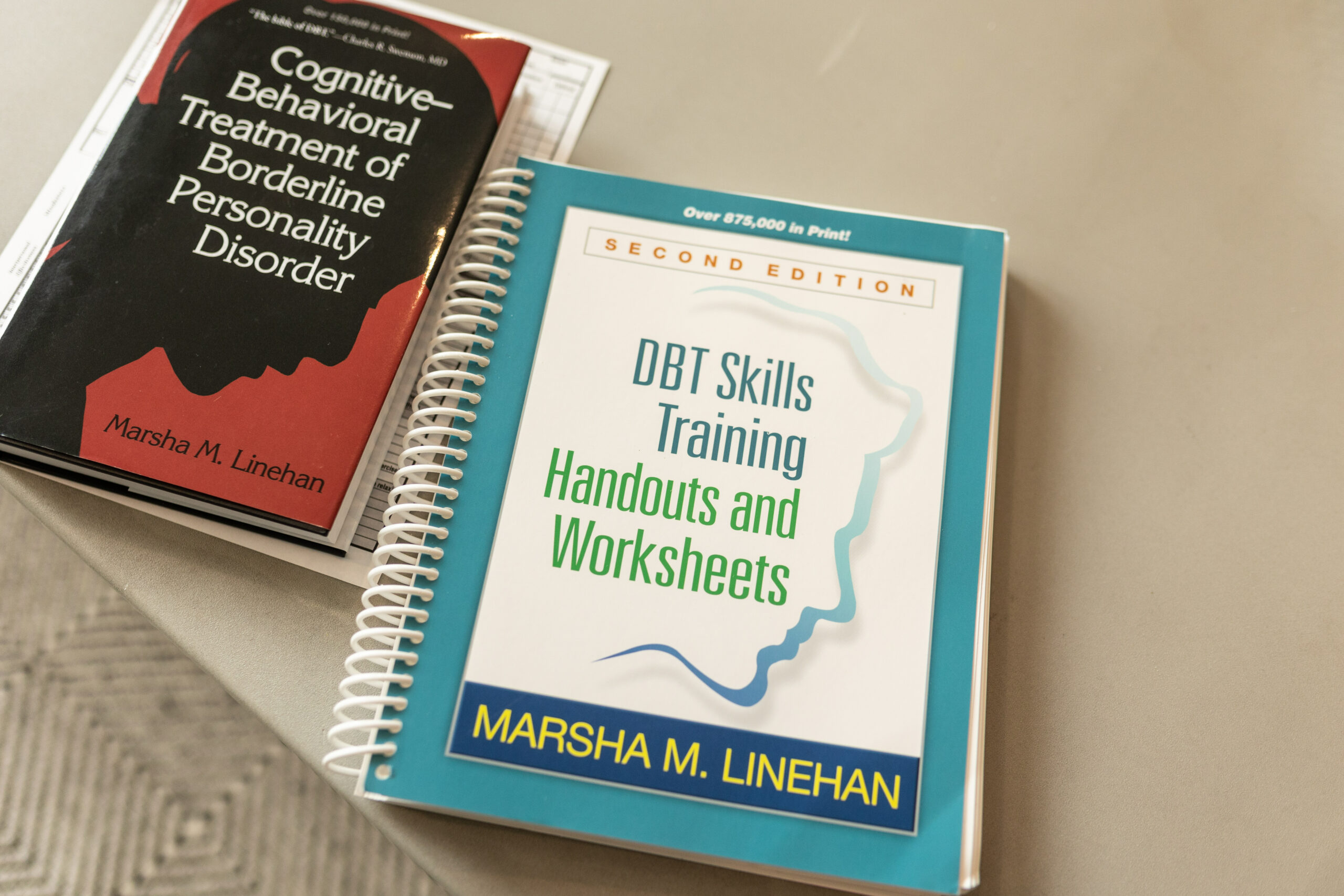 Two borderline personality disorder DBT treatment books on top of a DBT diary card
