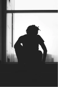Black and white silhouette photo of teen by window