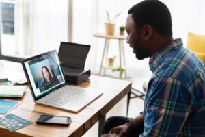 Man sitting at table with laptop having Telehealth session