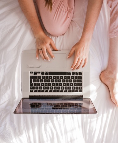 Girl sitting in her bed on laptop