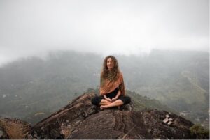 Woman sitting peacefully in nature practicing mindfulness, focusing on being in the moment