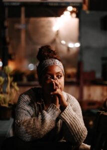 Girl sitting with her hands covering her face while looking off to the distance