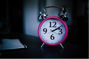 Old fashioned pink alarm clock on a side table