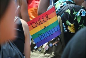 A rainbow flag that reads "QUEER & PROUD"