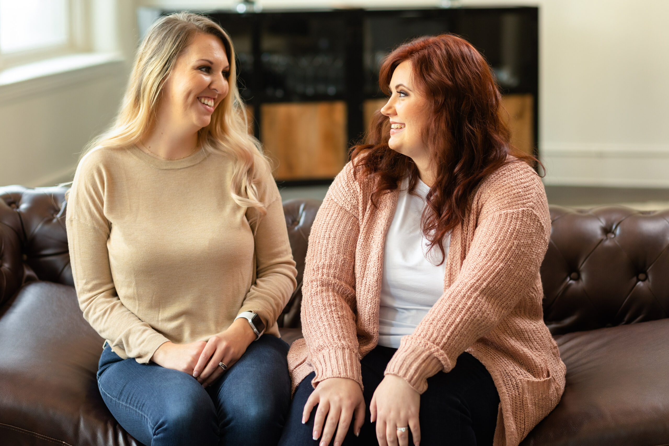 Drs. Nikki Winchester and Desirae Allen, DBT therapists and psychologists at Cincinnati Center for DBT, sit side-by-side smiling at each other as they discuss providing LGBTQIA+ affirming therapy