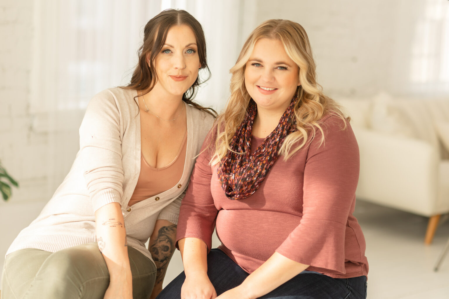 Two LGBTQIA+ DBT clinicians in Cincinnati sitting close to one another smiling at the camera.