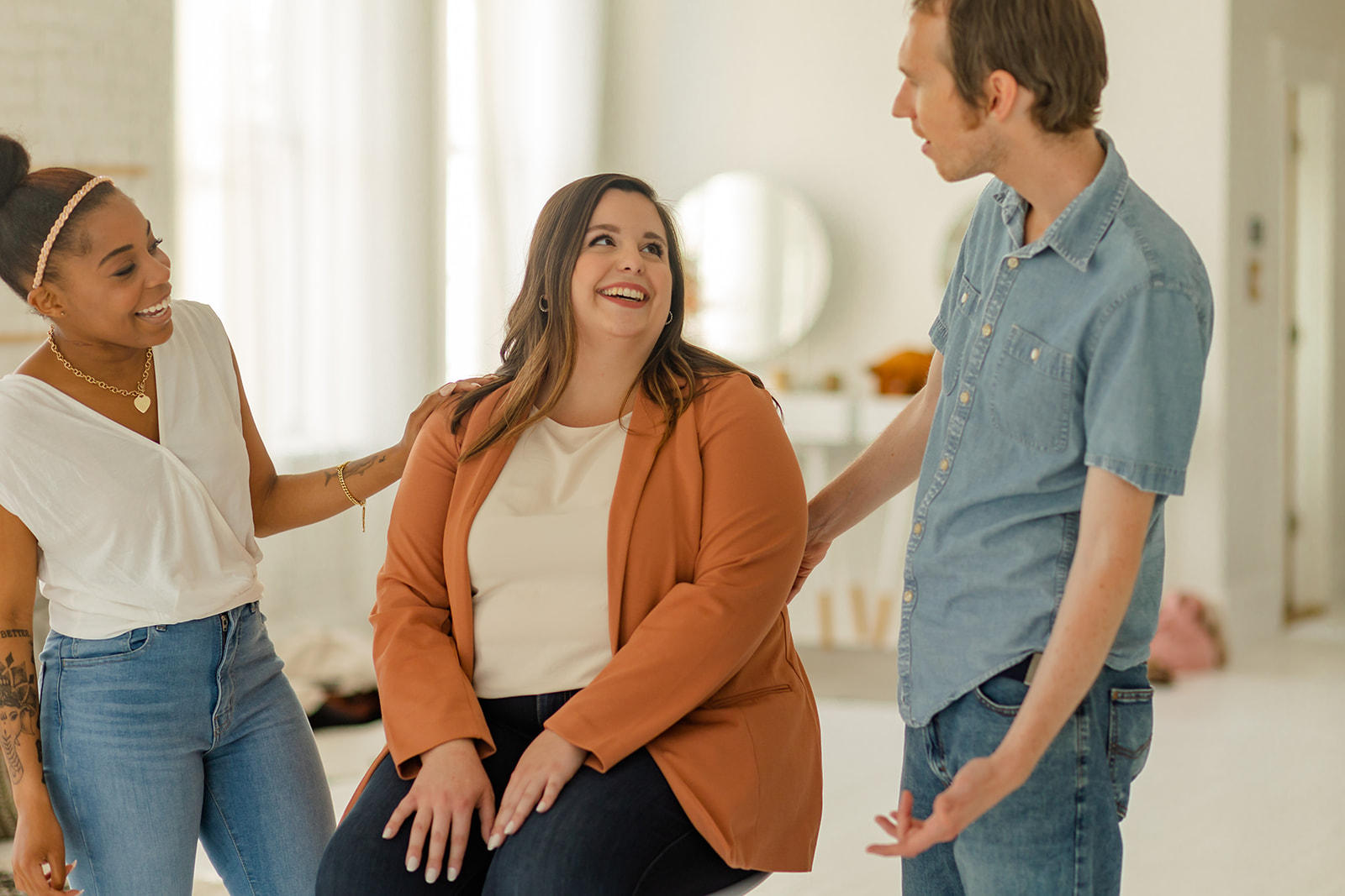 Three LGBTQIA+ DBT clinicians in Cincinnati talk to each other while arms touch someone's back