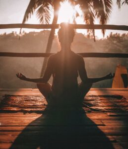 person sitting with arms out hands open sunset willing hands