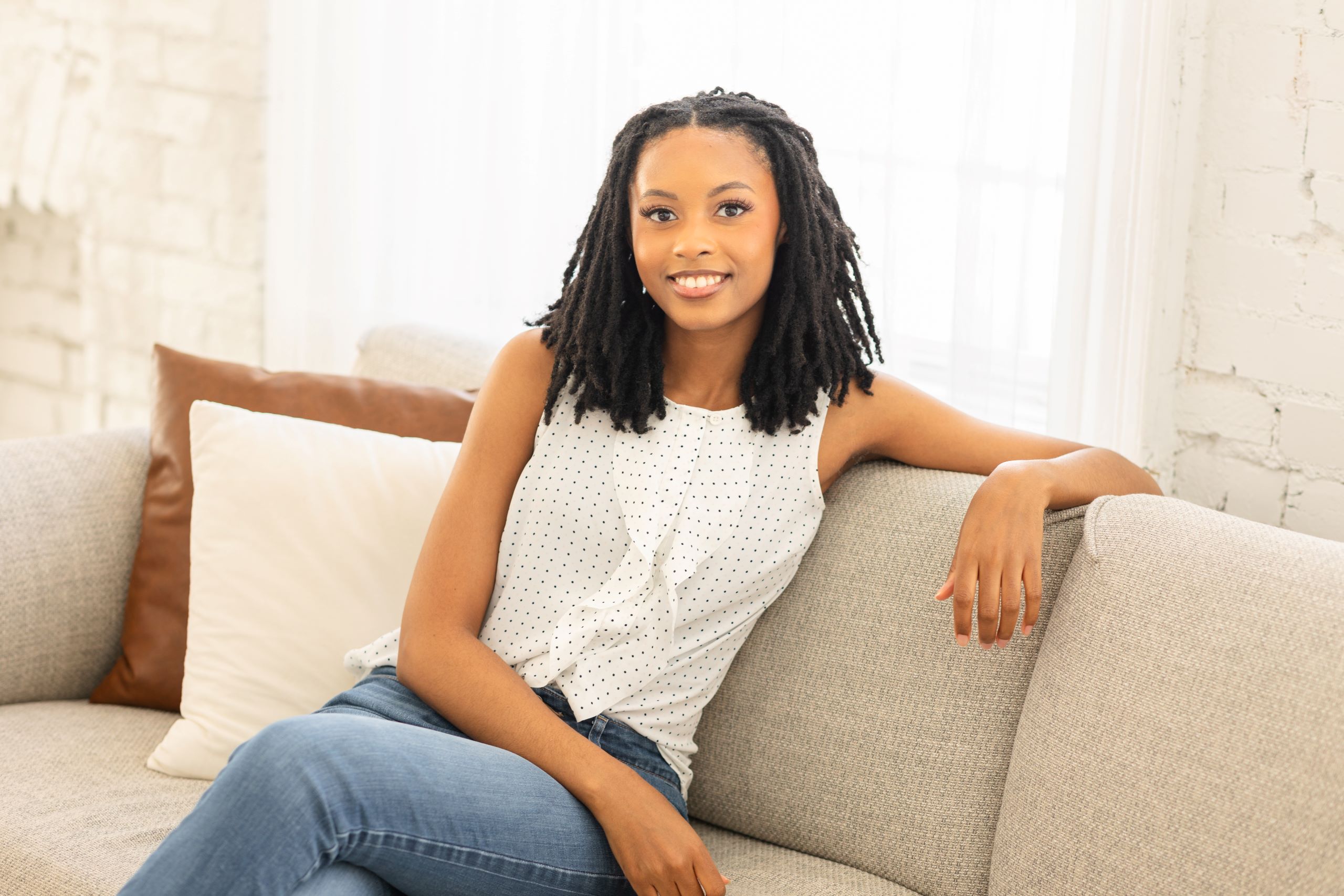 Adrianna Jones DBT Therapist Sitting on couch smiling