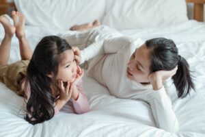 mom and daughter laying on bed talking