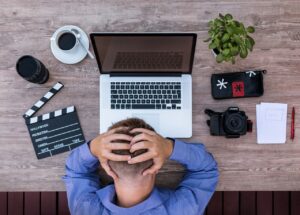 A man with his hands over his head in distress over his many tasks and conflicting schedule which may interfere with his therapy