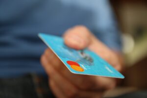 An individual holding on to their credit card in order to process a payment