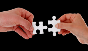 two hands fitting together puzzle pieces