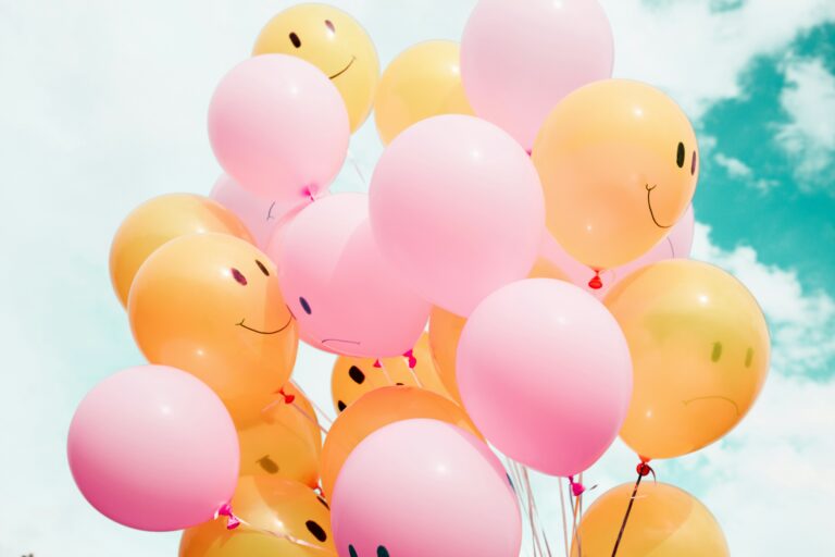 A group of colorful balloons with mostly smiley faces