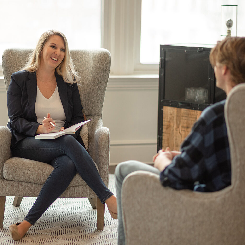 Dr. Desirae Allen, DBT therapist, sitting in an accent chair across from a DBT client, providing adherent DBT